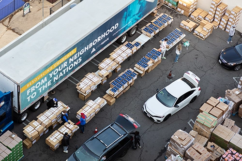 Aerial view of CityServe distribution event with trucks, boxes, and volunteers preparing essential supplies for local churches to distribute in their communities.